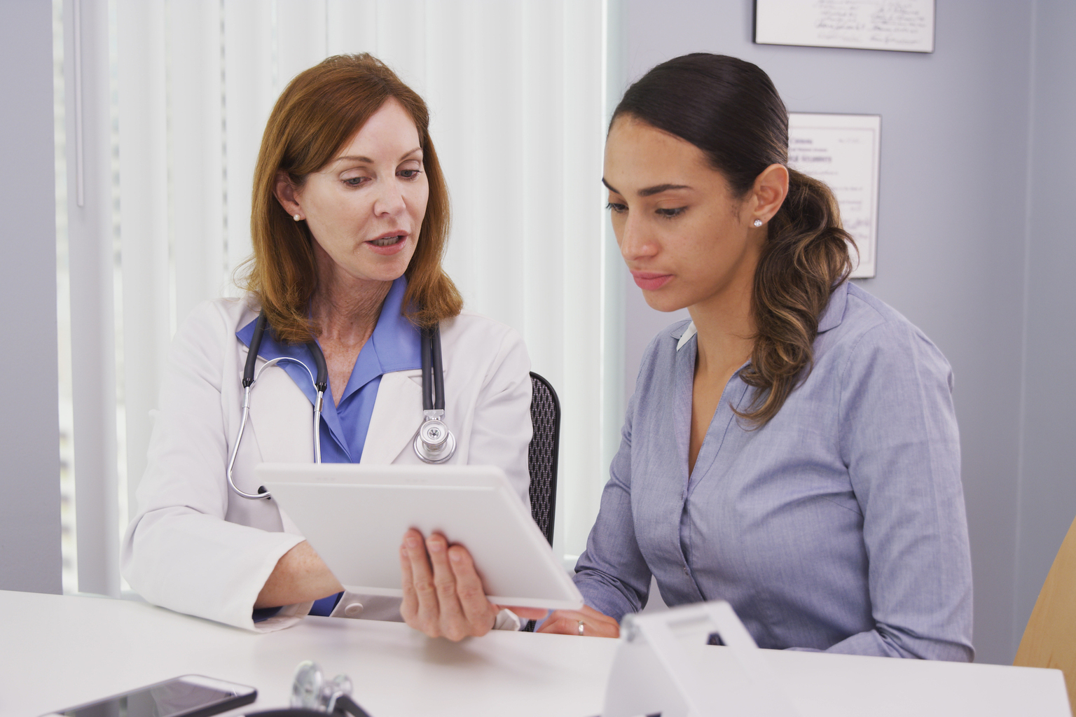 Latina patient consulting with doctor test results on portable tablet